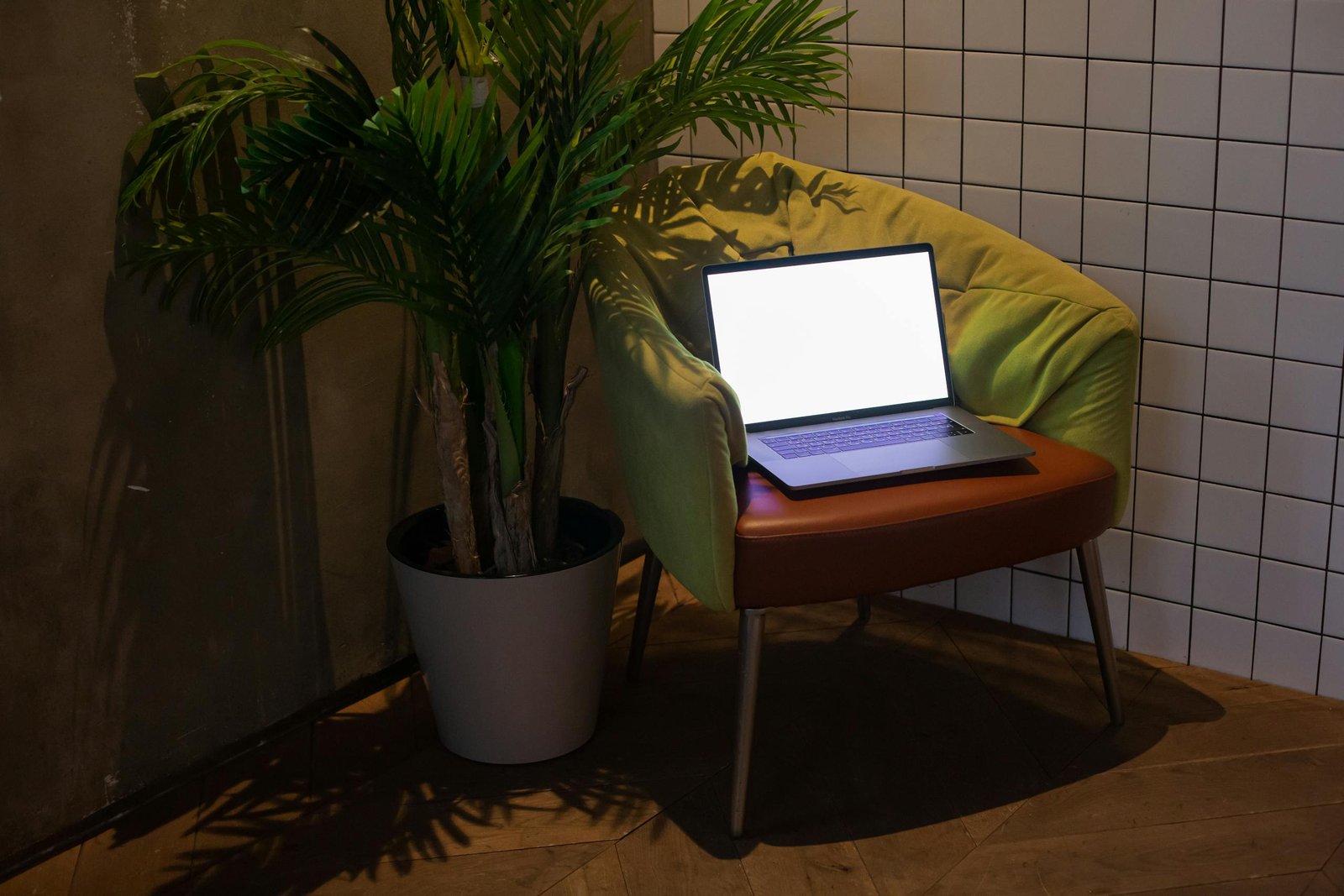 A cozy modern interior featuring a laptop on a stylish chair beside a potted plant.