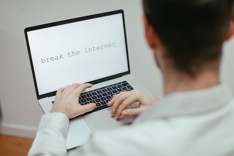 A person typing on a laptop showing the provocative message 'break the internet'.
